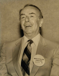 Man in suit and tie with button displaying his name